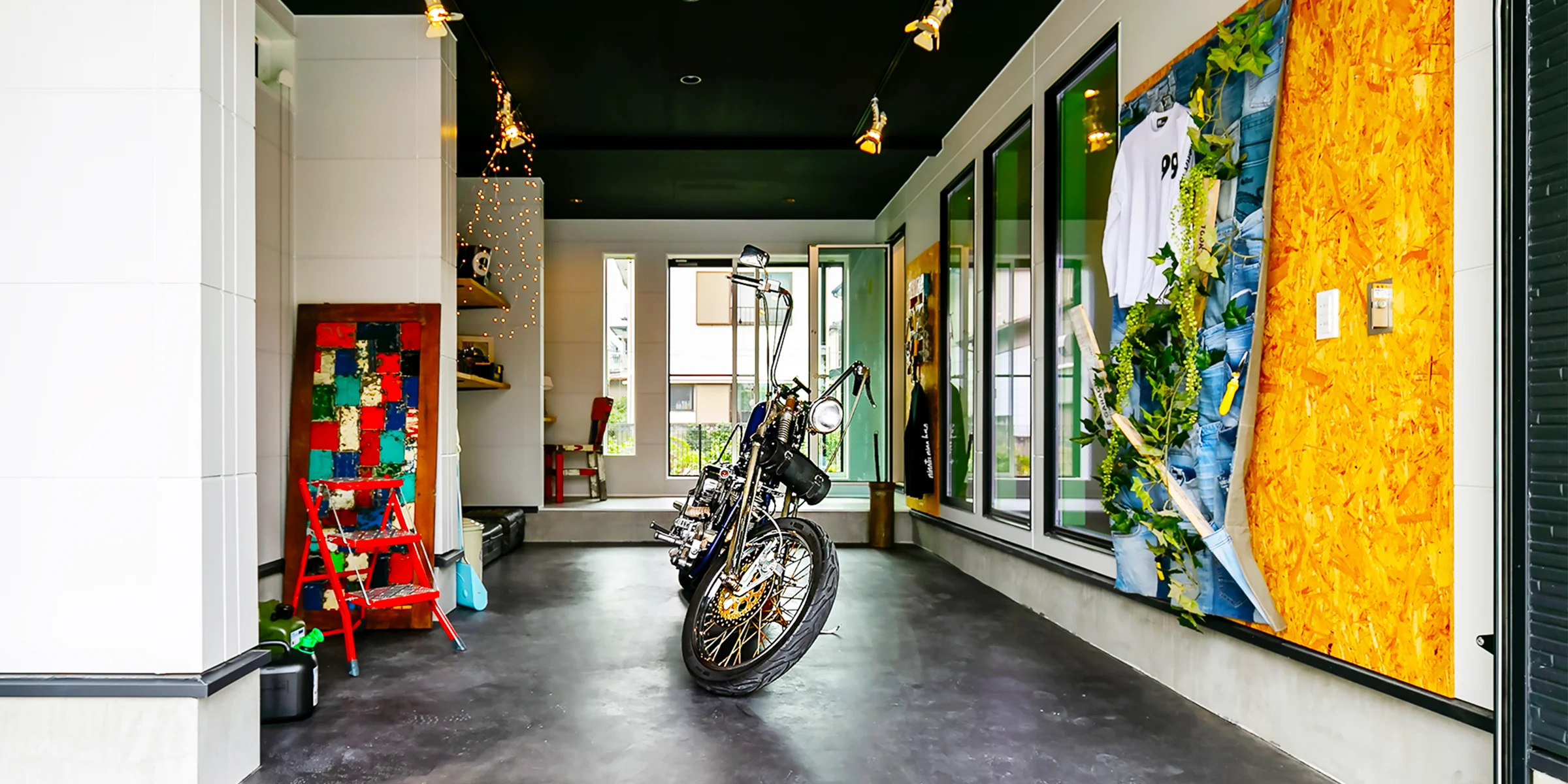 ガレージの内部。バイクを置き、壁面にアートパネルを飾ったモルタル床の土間空間