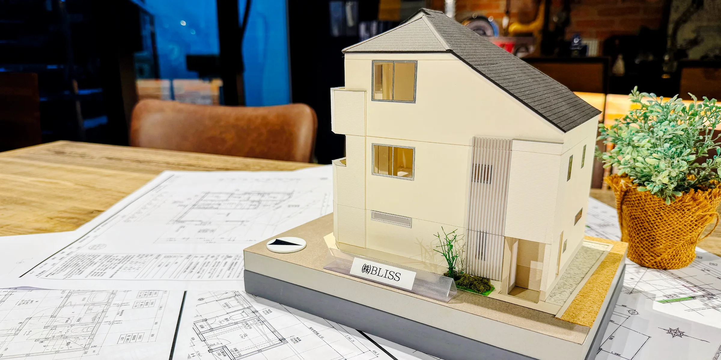 図面の上に置かれた切妻屋根の住宅模型