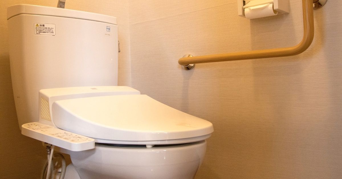 手すりがついているタンク付きのトイレ
