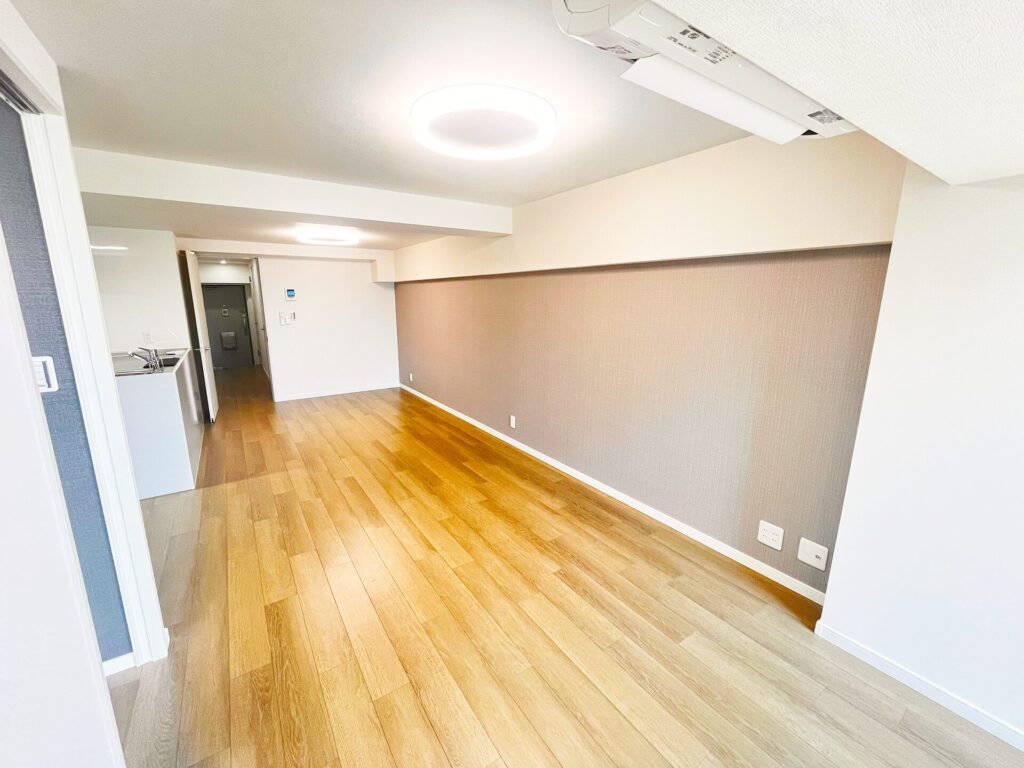 リフォーム後のLDK別角度。和室を取り込み広いワンルームに、アクセントクロスと木目フローリングでモダンな空間