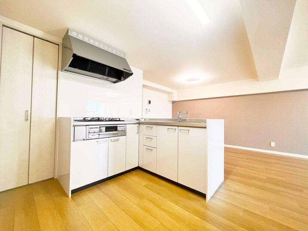 リフォーム後のキッチン。白いL型対面キッチンに刷新、大型レンジフードと収納力のある引き戸クローゼット