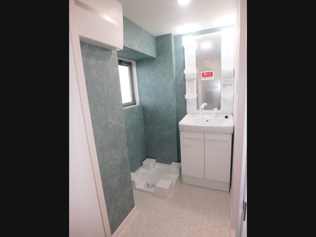 リフォーム後の独立洗面室。浴室から分離し、シャンプードレッサーと洗濯機置場を新設、グレーのクロスで爽やかな空間に