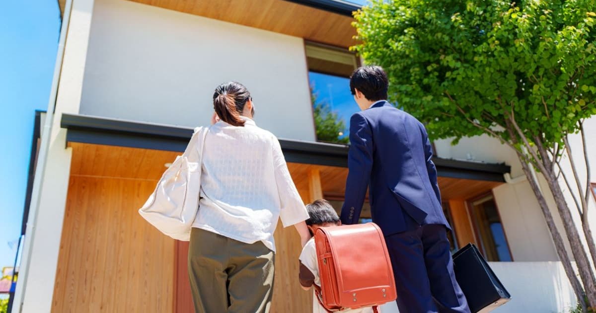 新築の一戸建てを見つめる若い夫婦と子ども