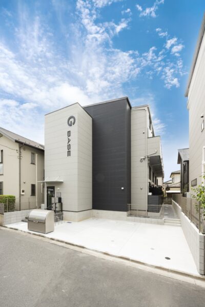 青空を背にしたグレーとブラックの外壁の集合住宅